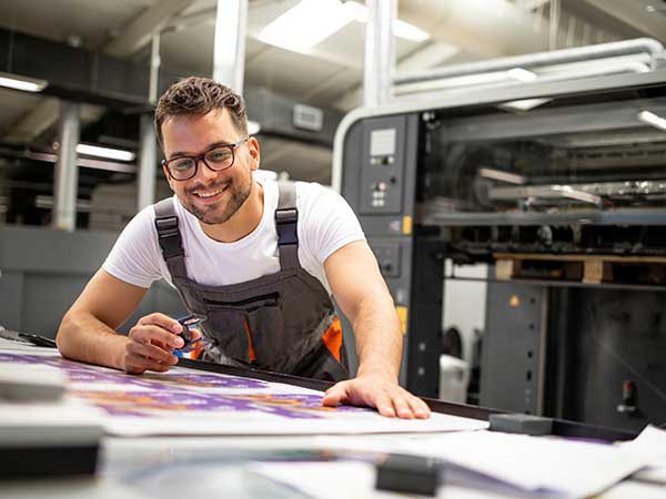man looking over a print job at a manufacturing facility