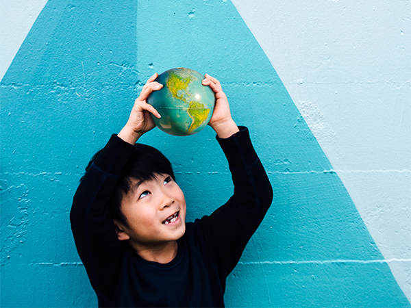 Young boy holding up a small ball that looks like earth
