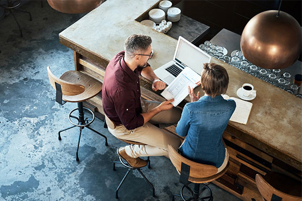 High angle shot of two businesspeople working at the bar in a cafe