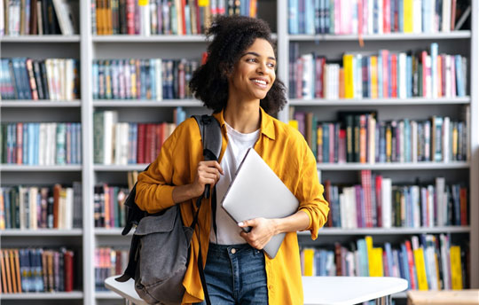 woman standing in library with laptop