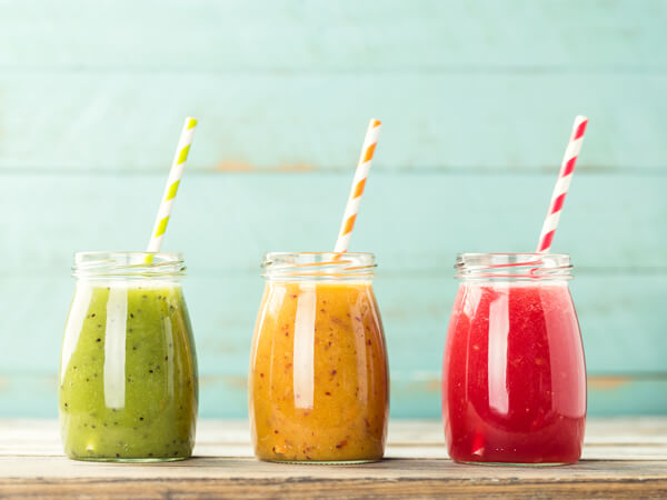 green, yellow, and red smoothies lined up on a table