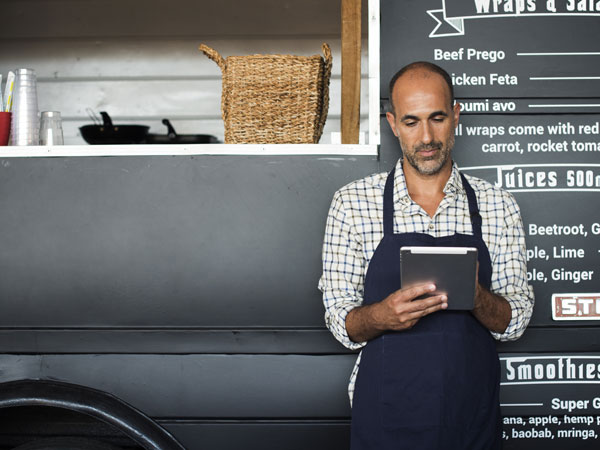 Man holding an ipad standing in front of food truck