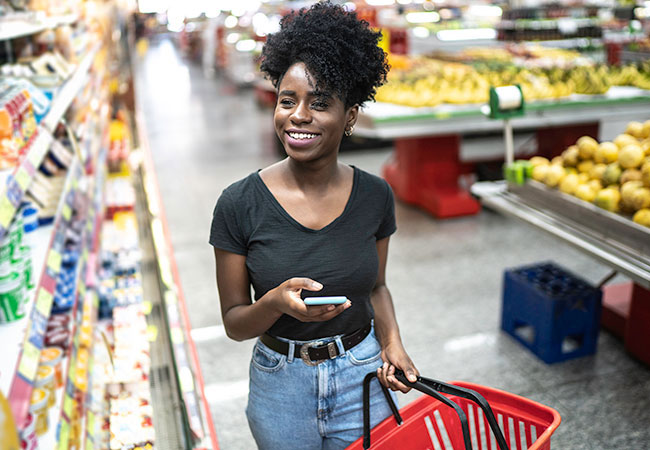 woman walking through a grocery store her phone