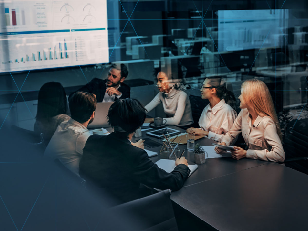 business people sitting at a conference table looking at a projection of a presentation