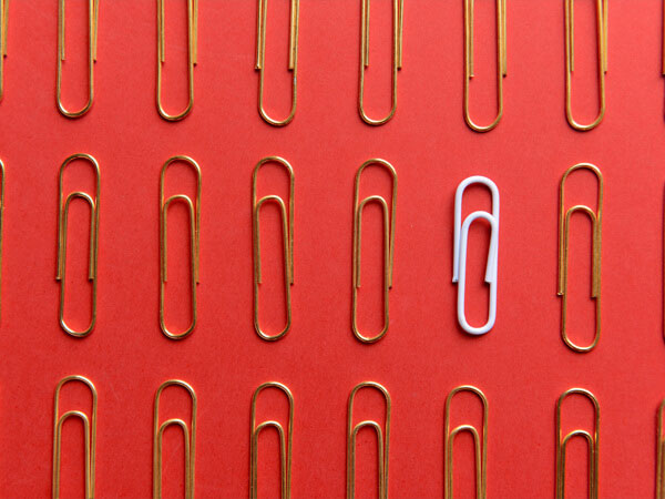 one white paperclip standing out in a sea of gold paperclips