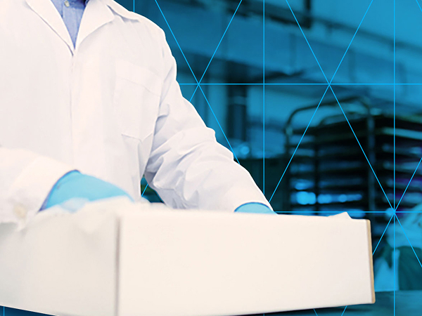 Lab technician in a white coat and gloves handling a white box in a laboratory setting