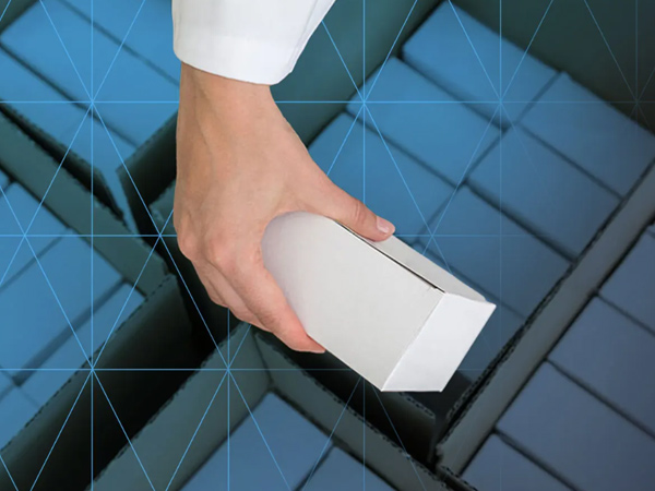 hand placing a white rectangular box into a larger box