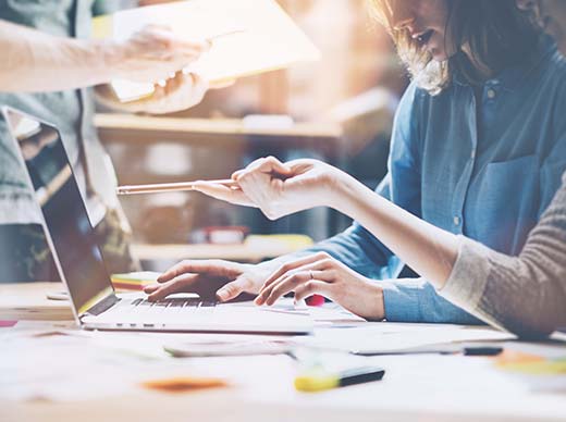 two woman brainstorming at a laptop