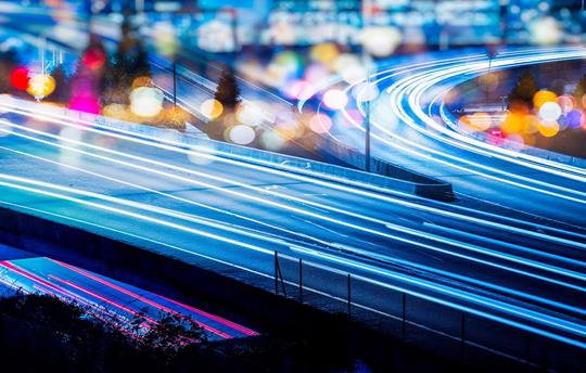 city highway at night with light trails on the road signifying movement