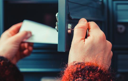 a person opening a mailbox and retrieving a piece of mail