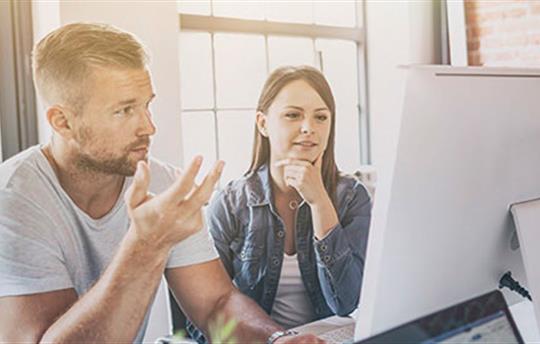 Man and woman coworkers discussing what they're seeing on a computer screen