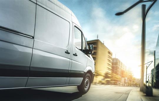white sprinter van driving down city street