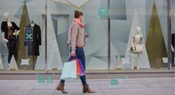 shopper walking passed a window display considering different products